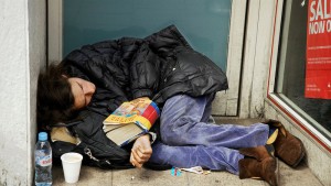 Beggar sleeping in a doorway next to a bank cash machine in Hackney.